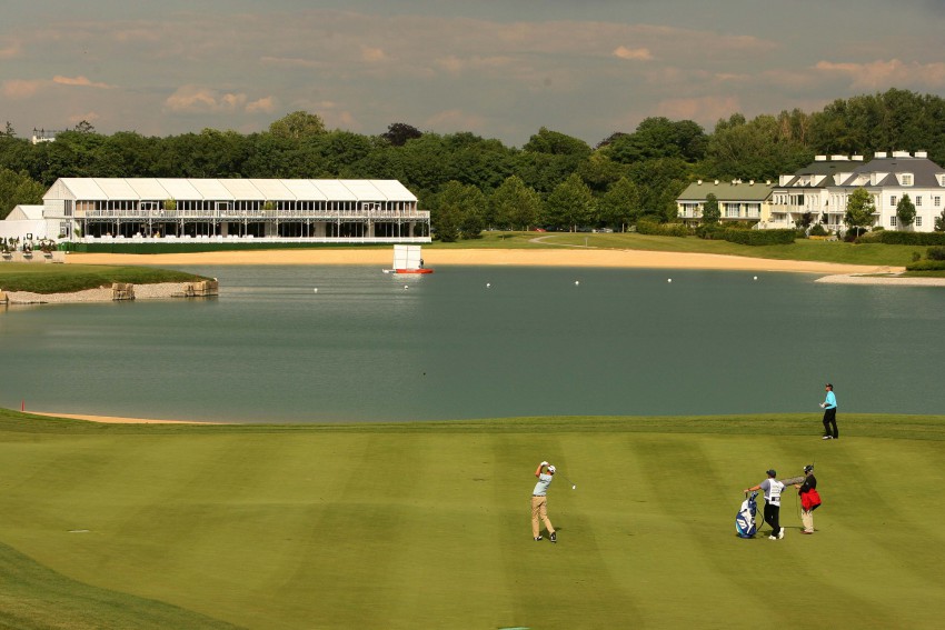 Skupina štirih golfistov med igro golfa pred velikim jezerom in s pogledom na prestižne vile, ki obdajajo igrišče Fontana po vzoru ameriških klubov.