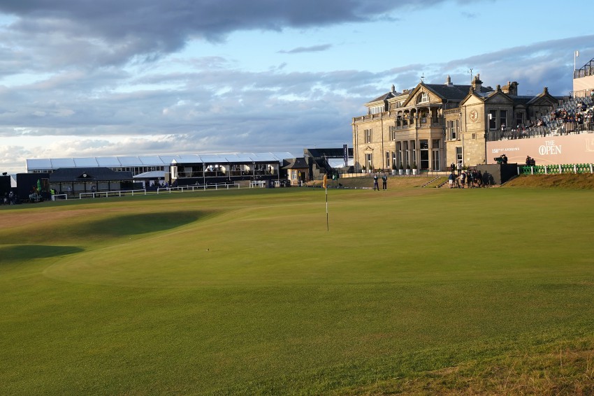 Pogled na luknjo na golf igrišču  St Andrews na Škotskem, v ozadju tribuna za gledalce turnirja in čudovita stara klubska stavba. 